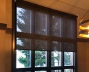 Полупрозрачные коричневые рулонные шторы установлены на коричневые окна