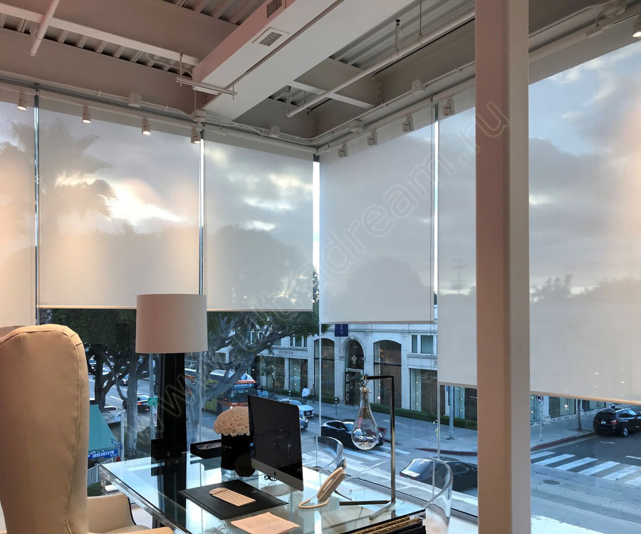 В офисном помещении с панорамным остеклением установили полупрозрачные светло-бежевые рулонные шторы