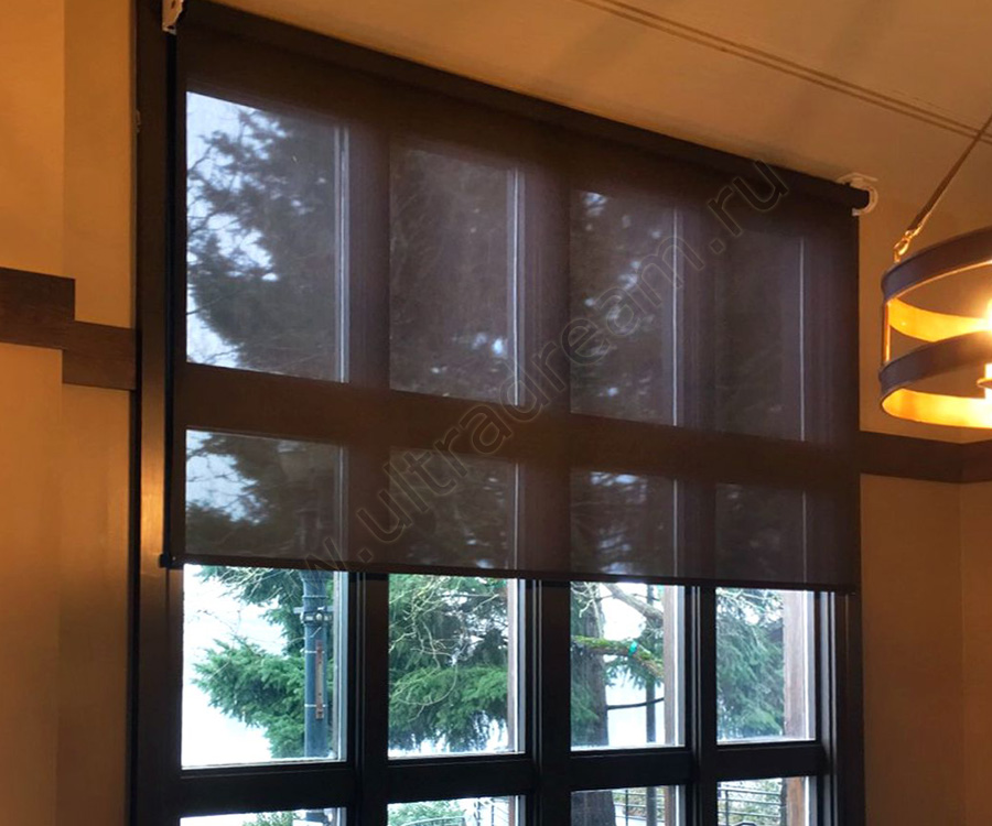 Полупрозрачные коричневые рулонные шторы установлены на коричневые окна