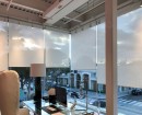 В офисном помещении с панорамным остеклением установили полупрозрачные светло-бежевые рулонные шторы