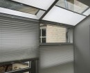 Серые шторы плиссе натяжного типа установлены на наклонные и обычные окна