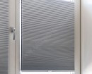 Серые светонепроницаемые натяжные шторы плиссе на створках окна