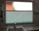 Натяжная штора плиссе белого цвета и голубоватым оттенком установлена на кухне